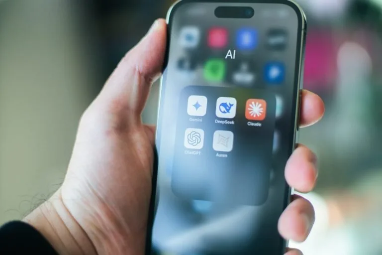 A hand holds a smartphone with various apps.